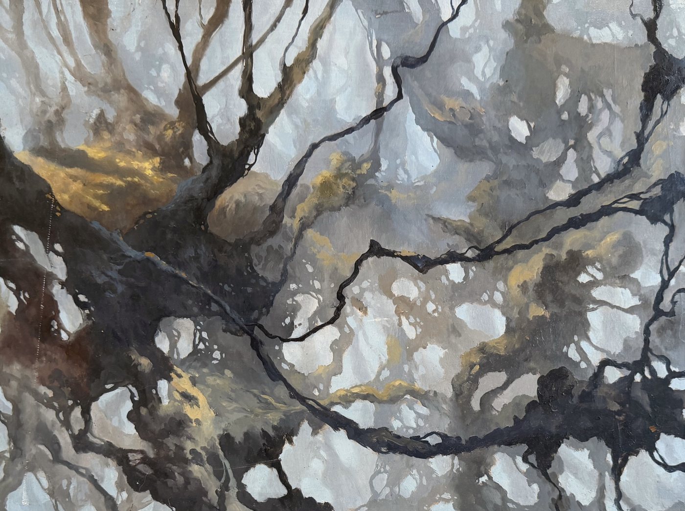 Réseau de branches noires et d'or sur une brume claire.